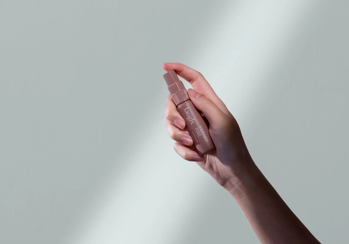 手が淡いピンク色の小さなスプレーボトルを持っている画像