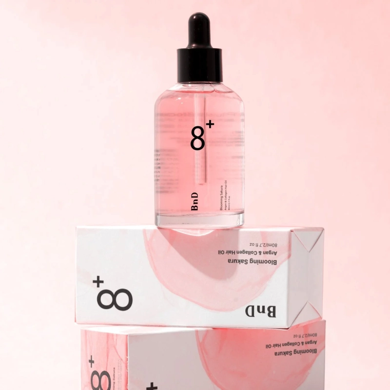 ピンク色の背景に、桜のデザインが施されたBnDのヘアオイルボトルと、同じデザインの外箱
