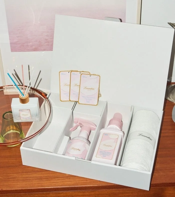 白いギフトボックスに、ランドリンのルームフレグランス、スプレー、液体洗剤、エアフレッシュナー、タオルが収められています。清潔感のあるピンクと白を基調としたセットです。