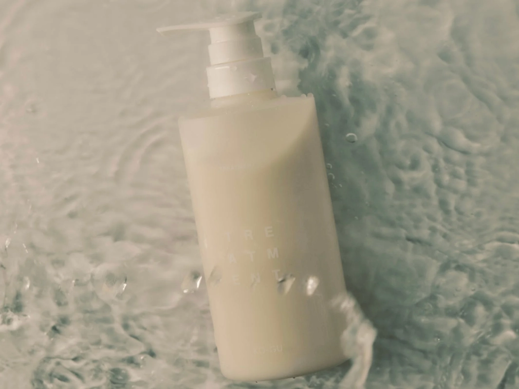 水中に浮かぶ白いポンプ式ボトル「TREATMENT KO-GU」