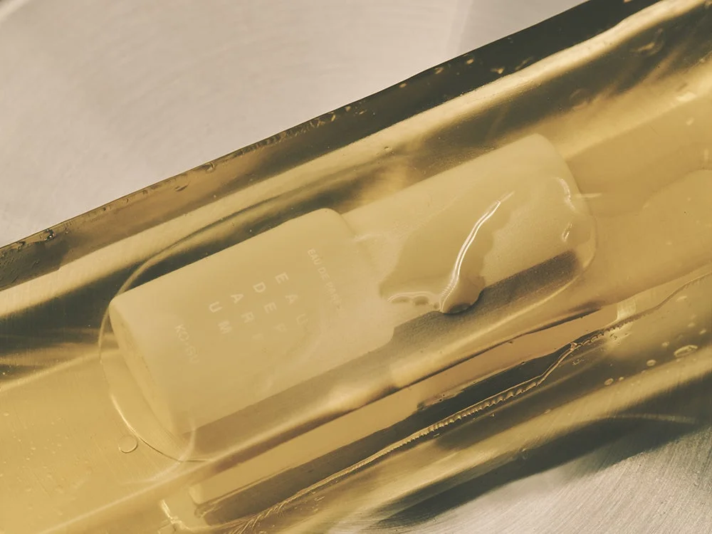 金色の光沢のある背景に、半透明の白い香水ボトル